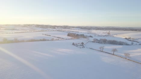 Winterlandschaft-Mit-Einem-Haus-Und-Feldern,-Die-An-Einem-Hellen,-Kalten-Tag-In-Schottland-Während-Der-Goldenen-Stunde-Bis-Zum-Horizont-Mit-Weißem-Schnee-Bedeckt-Sind