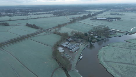 Aerial-of-farm-on-river-shore-in-a-beautiful-frost-covered-landscape