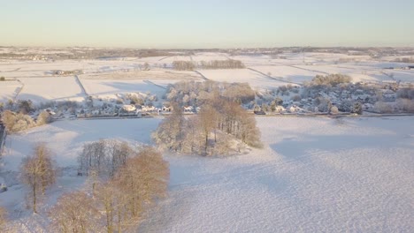 Winter-landscape-near-a-village-with-big-houses-and-fields-covered-with-white-snow-on-a-bright-cold-day-in-Scotland-during-golden-hour
