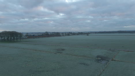 Aerial-of-frozen-rural-landscape-with-a-train-running-through-the-background