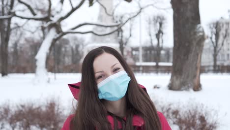 Dame-In-Chirurgischer-Maske-Lächelt-Während-Eines-Fröhlichen-Tagesspaziergangs-Im-Winterpark