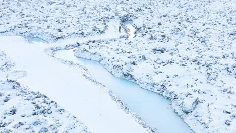 Winter-scenery-in-Iceland-with-surface-covered-in-snow-at-blue-geothermal-river