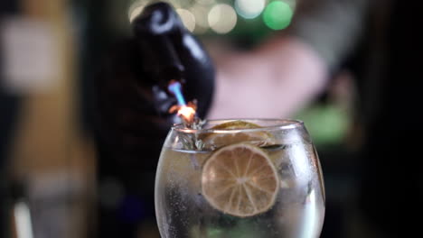 Barkeeper-Mixologist-Rauchen-Flammenden-Rosmarin-Garnieren-Zitrusfrüchte-Wodka-Tonic-Cocktail-Zeitlupe-Nahaufnahme