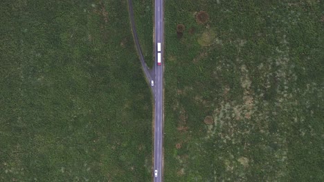 Top-down-of-cars-traveling-on-straight-road-through-green-arctic-meadow