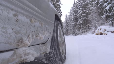 Close-up-of-car-wheel-driving-on-a-snowy-forest-road-without-tire-chains