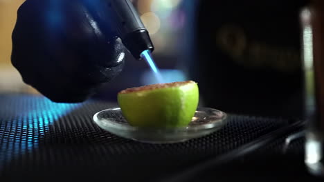 bartender-flaming-lemon-citrus-with-sugar-for-cocktail-preparation-slow-motion