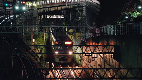 Trains-On-Railway-Track-With-Headlights-On-At-Night-In-City-Of-Tokyo,-Japan