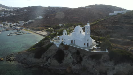 Circling-drone-aerial-shot-of-White-church-in-the-Port-of-Ios,-Greece-near-Chora