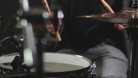 Smooth-slow-motion-of-a-drum-set-being-played-in-front-of-a-dark-background-while-camera-makes-a-panning-gimbal-movement