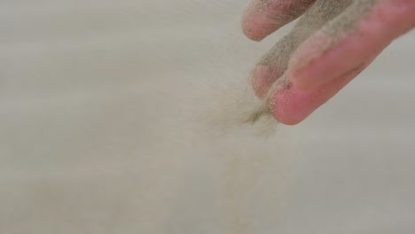 Slow-motion-close-up-of-a-man's-hand-as-he-releases-sand-into-the-wind
