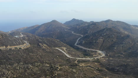 Drone-aerial-shot-of-mountainous-island-of-Ios,-Greece,-with-curvy-mountain-road