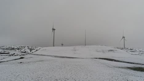 Campo-De-Montaña-De-Invierno-Turbinas-De-Viento-En-Las-Tierras-Altas-Rurales-Vista-Aérea-Frío-Tormenta-De-Nieve-Valle-Ladera-Creciente
