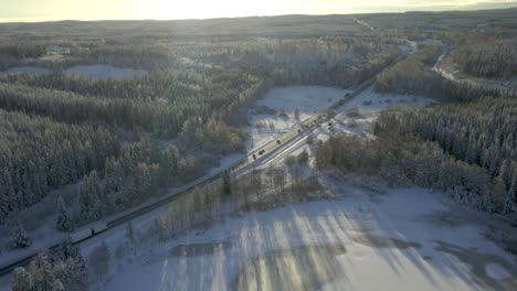 Forward-dolly-showing-a-country-road-with-cars-and-trucks-driving-surrounded-by-a-Snowy-landscape