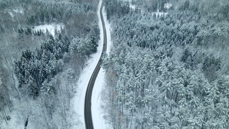 Aerial-pan-shot-showing-cars-driving-on-scenic-winter-road-during-beautiful-snowy-day-with-snow-and-ice
