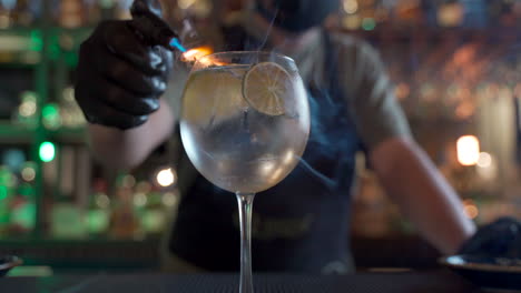Lateinischer-Barkeeper,-Der-Zitrus-Wodka-Tonikum-Raucht,-Flammender,-Verschwommener-Bar-Hintergrund