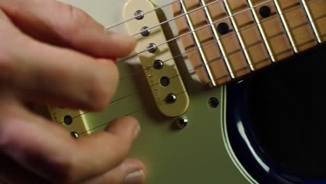 Zeitlupe-Nahaufnahme-Des-Halses-Und-Der-Saiten-Einer-Elektrischen-Stratocaster-Gitarre-Und-Der-Hände-Des-Gitarristen-Beim-Spielen-Von-Noten-Mit-Einem-Plektrum