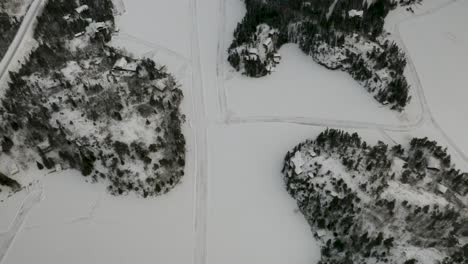 Luftaufnahme-Eines-Netzes-Winterlicher-Eisstraßen,-Die-über-Einen-Zugefrorenen-See-In-Den-Nördlichen-Borealen-Wäldern-Kanadas-Verstreut-Sind