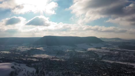 Luftflug-über-Winterwunderland-In-Richtung-Berge-Und-Sonne,-Die-In-Der-Kamera-Mit-Blick-Auf-Die-Atemberaubende-Landschaft-In-Schwaben,-Deutschland,-Reflektiert-Wird