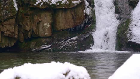 Breathtaking-waterfall-in-snow-covered-landscape-while-snowing-in-winter,-static-shot