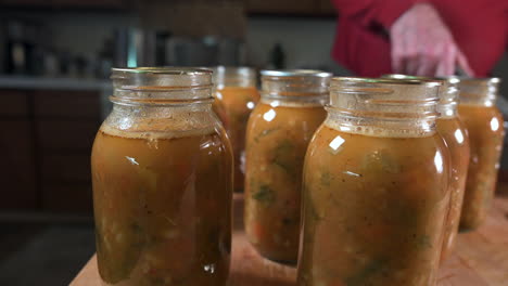 Home-Canning---Man-Puts-Sterile-Canning-Lids-On-Mason-Jars-With-Minestrone-Soup---close-up