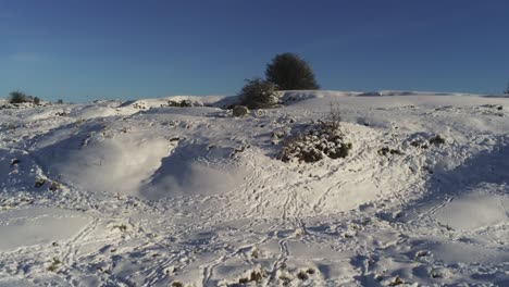 Schneebedeckte-Ländliche-Winterlandschaft-Spur-Spur-Schatten-Gelände-Luftaufnahme-Langsam-Schieben-In-Steigend