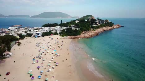 A-moving-aerial-view-of-visitors-using-umbrellas-at-the-Shek-O-beach-in-Hong-Kong-as-public-beaches-reopening,-after-months-of-closure-amid-coronavirus-outbreak,-to-the-public