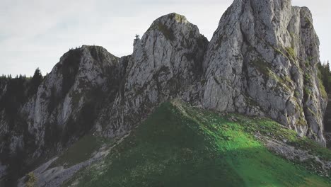Tilt-up-camera-movement-showing-a-green-meadow-and-mountain-cliffs-at-sunset-in-the-Buila-Vanturarita-Carpathian-Mountains
