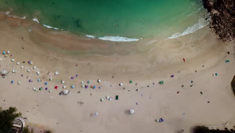 A-moving-aerial-view-of-visitors-using-umbrellas-at-the-Shek-O-beach-in-Hong-Kong-as-public-beaches-reopening,-after-months-of-closure-amid-coronavirus-outbreak,-to-the-public