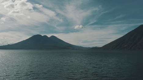 Drone-aerial-panning-over-lake-Atitlan,-3-volcanoes-in-the-background-in-Guatemala