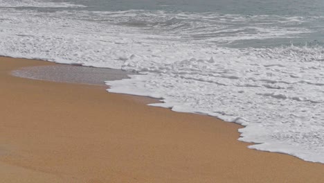 Zeitlupenwellen-Weiß-Mit-Schaum-Bedecken-Den-Nassen-Sand-Des-Strandes,-Portugal