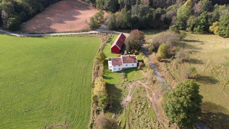 Aerial-view-of-Swedish-countryside-landscape-with-rural-house-by-open-field,-day