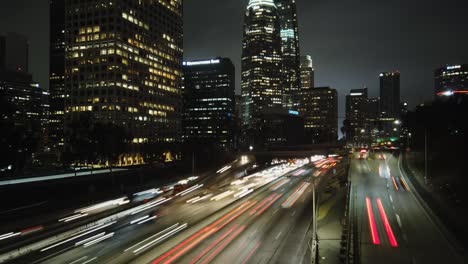 Time-lapse,-downtown-Los-Angeles-over-freeway-with-traffic,-nighttime-city-view,-panning-left