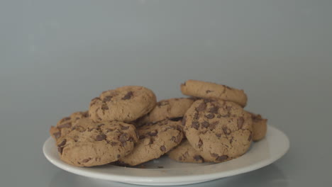Hand-taking-chocolate-chip-cookies-from-pile-of-cookies---wide