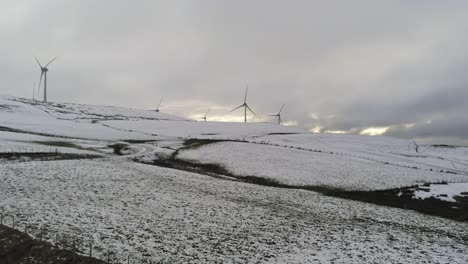 Winterberglandschaft-Windkraftanlagen-Auf-Ländlichem-Hochland-Antenne-Rechts-Schwenkansicht-Kalt-Verschneiten-Talhang