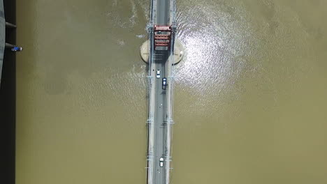 High-Angle-Aerial-View-of-Traffic-on-Suspension-Bridge-Above-Muddy-River-Water