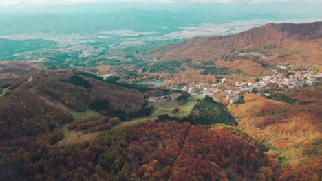 Distant-View-Of-Okama-Crater-In-Zao-Onsen-Surrounded-By-Mountain-Forest-In-Fall-Colours---Autumn-In-Yamagata-City---aerial