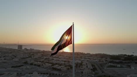 Drohnenansicht:-Silhouette,-Flagge-Der-Vereinigten-Arabischen-Emirate,-Die-In-Der-Luft-Weht,-Himmel-Und-Sonnenhintergrund,-Das-Nationale-Symbol-Der-Vereinigten-Arabischen-Emirate