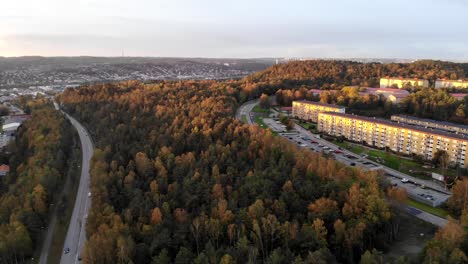 Sunset-aerial-forest-pull-back-shot-with-high-rise-city-housing-blocks