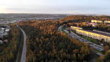Scenic-aerial-drone-flying-above-suburban-road-in-Gothenburg,-Sweden,-sunset