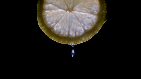 A-dripping-lemon-slice-isolated-on-a-black-background-with-copyspace
