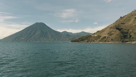 Drone-aerial-view-of-beautiful-lake-Atitlan,-Guatemala-surrounded-by-volcanoes-and-mountains