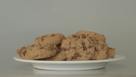 Hand-placing-chocolate-chip-cookies-on-a-white-plate