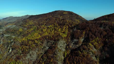 Bunter-Berg-Mit-Gelbbraunen-Bäumen-Und-Felsigen-Hängen-Mit-Hellblauem-Himmelshintergrund