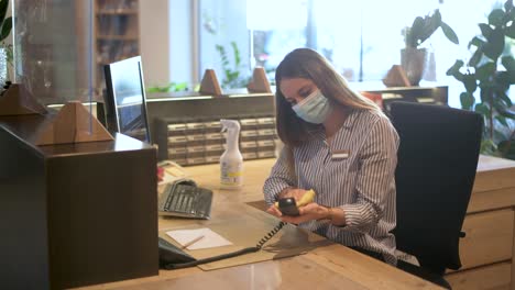 Receptionist---office-employee-is-cleaning-the-workplace-and-disinfects-the-phone---COVID-19-tourism-footage