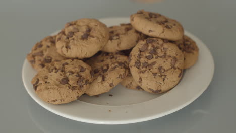 Hand-placing-chocolate-chip-cookies-on-pile-of-cookies---high-angle