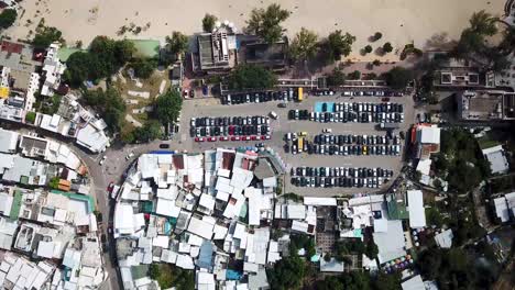 A-moving-aerial-view-of-Shek-O-village,-beach-and-of-visitors-using-umbrellas-in-Hong-Kong-as-public-beaches-reopening,-after-months-of-closure-amid-coronavirus-outbreak,-to-the-public