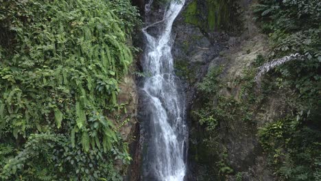 Ascending-low-angle-medium-drone-shot-of-a-beautiful-waterfall-hidden-in-the-tropical-rainforest-jungle