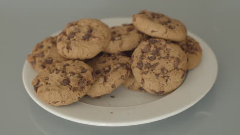 Hand-taking-chocolate-chip-cookies-from-a-white-plate---high-angle