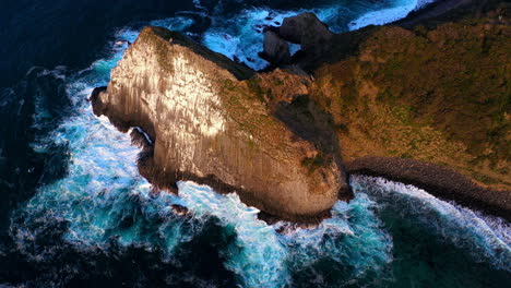 Filmische-Drohnenaufnahme-Von-Wellen,-Die-Gegen-Große-Steine-Im-Wasser-Bei-Kyushu-Japan-Prallen