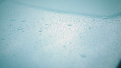 Macro-slider-shot-of-rain-droplets-on-blue-metal-car-hood-shot-in-25-fps